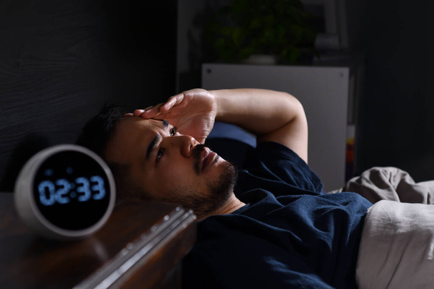 Depressed young Asian man lying in bed cannot sleep from insomnia - Photo, Image
