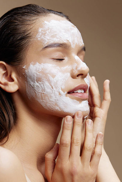 young woman with cream on face on  isolated background. High quality photo - Photo, Image
