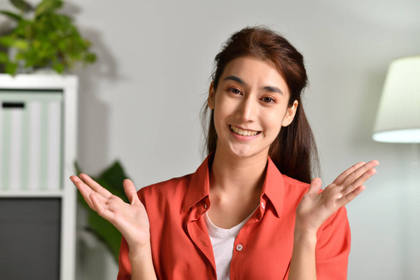 Portrait shot of happy friendly and confident Asian businesswoman making video call, looking at camera and talking, discussing strategy with partners online at home - 写真・画像