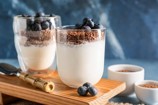 Bril van zoete yoghurt, lijnzaad en bosbessen op achtergrond van kleur, close-up - Foto, afbeelding