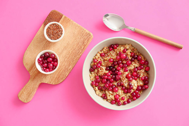 Bowl with tasty oatmeal, flax seeds and cranberries on color background - Photo, Image