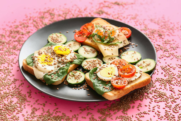 Plate with tasty toasts and flax seeds on color background - Photo, Image