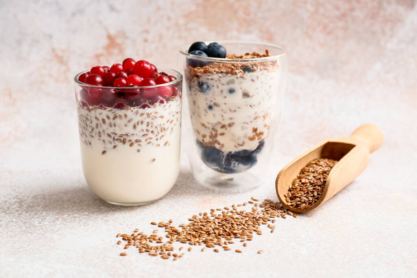 Gläser mit süßem Joghurt, Leinsamen und Blaubeeren auf hellem Hintergrund - Foto, Bild