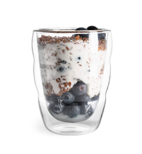 Glas met zoete yoghurt, lijnzaad en bosbessen op witte achtergrond - Foto, afbeelding