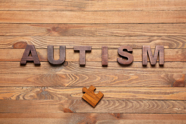 Word AUTISM and puzzle piece on wooden background - Foto, Imagem