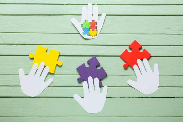 Papír lidské dlaně s barevnými puzzle kousky na barevném dřevěném pozadí. Koncept autistické poruchy - Fotografie, Obrázek