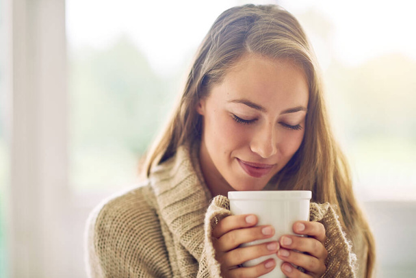 Having a cup of sereni-tea. Shot of a young woman enjoying a warm beverage at home. - Photo, Image