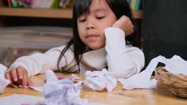 Overstuur meisje maakt een kleurrijke tekening thuis en verkruimelde het papier op het bureau. Meisjes die zich vervelen met online leren en huiswerk tijdens de coronavirus pandemie. - Video