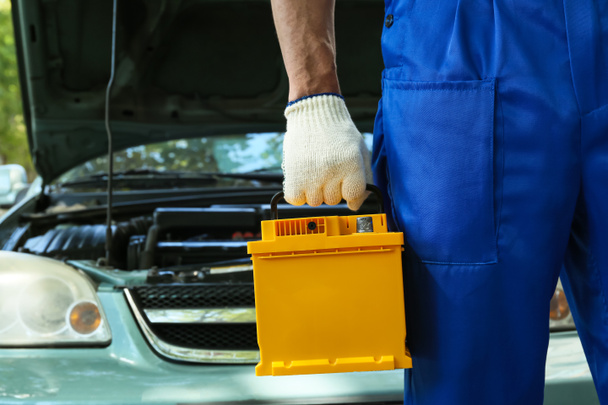 Male mechanic with modern car battery outdoors, closeup - Photo, image