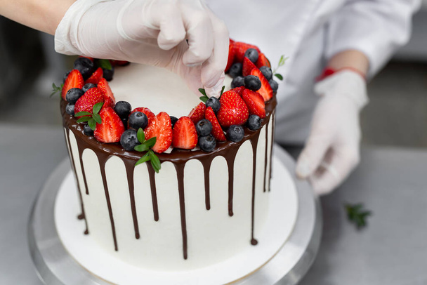 Pastry chef decorates the cake with chocolate levels of berries and mint - Φωτογραφία, εικόνα