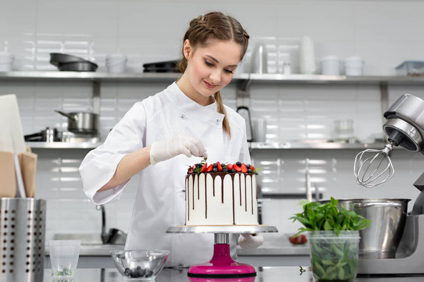 Pastry chef decorates the cake with chocolate levels of berries and mint - Valokuva, kuva