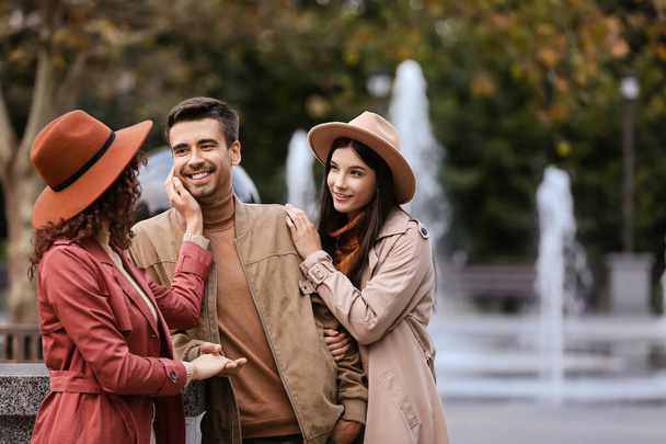 Man with two beautiful women in park. Polyamory concept - Foto, Imagem
