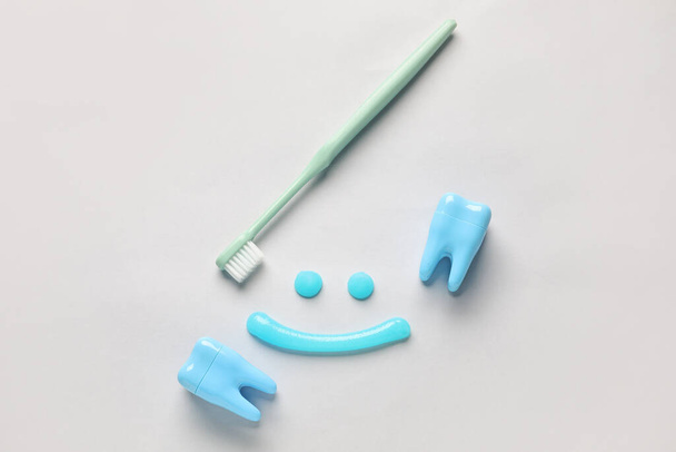 Sonrisa hecha de pasta de dientes, cepillo y dientes de plástico sobre fondo claro - Foto, imagen