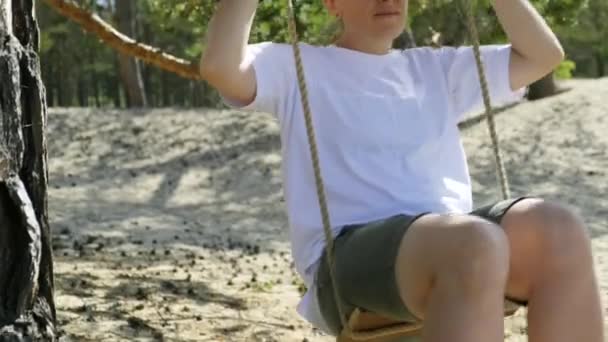 Jeune femme se balançant sur une balançoire de corde par une journée d'été ensoleillée. Mouvement lent - Séquence, vidéo