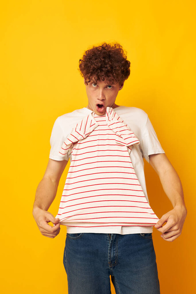 Young curly-haired man striped t shirt posing summer clothing yellow background unaltered - Foto, immagini
