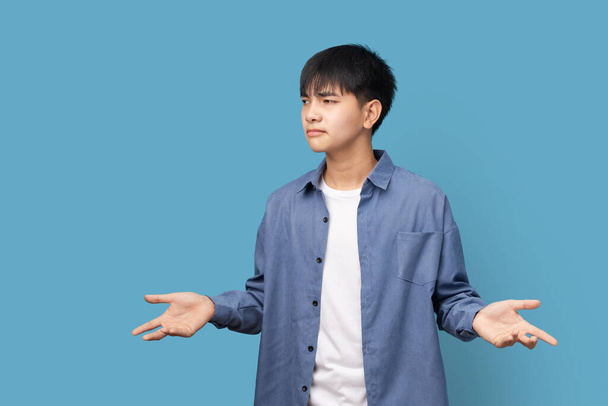 Portrait de jeune homme asiatique beau penser pensées et regarder de côté avec l'espace de copie debout sur fond bleu, penser à quelque chose. - Photo, image