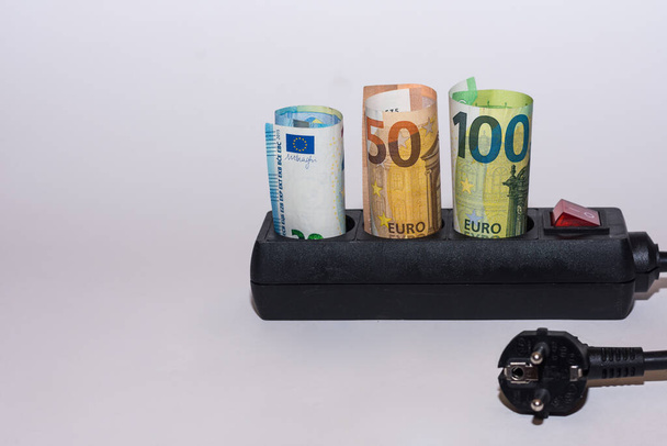 Energieverbruik en stijging van de elektriciteitsprijzen drie Euro rekeningen in een strook met stekker rechts - Foto, afbeelding