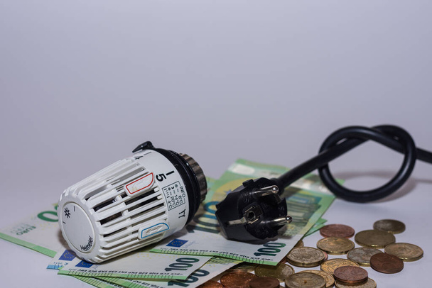 Energieprijzen stijgen en energieverbruik thermostatische regelaar verwarming en stekker met een knoop en geld met grijze achtergrond - Foto, afbeelding