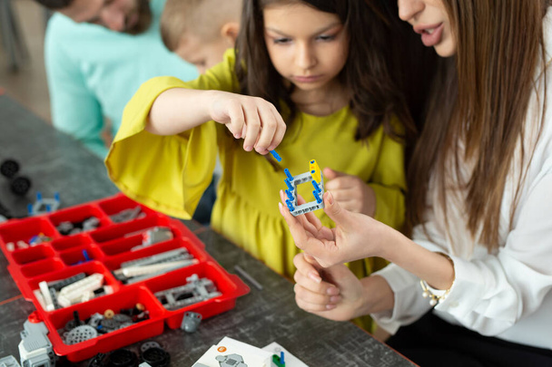 Close-up of a mother and daughters hands at school making a robot controlled from a construction kit - Foto, immagini