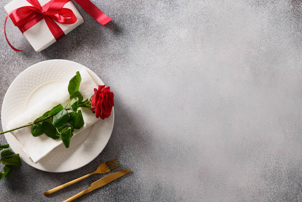 Valentine's day romantic dinner with red gift and red rose flower on gray background. Top view. Copy space. - 写真・画像