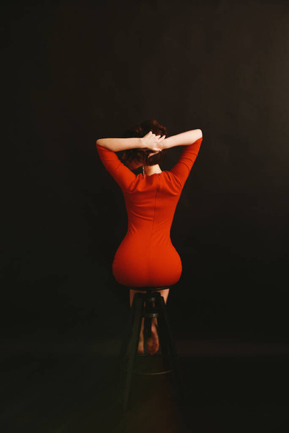 ein Mädchen in einem roten Kleid auf dunklem Hintergrund, Kunst und Mode, verschwommenes Foto und unscharfe Kunst - Foto, Bild