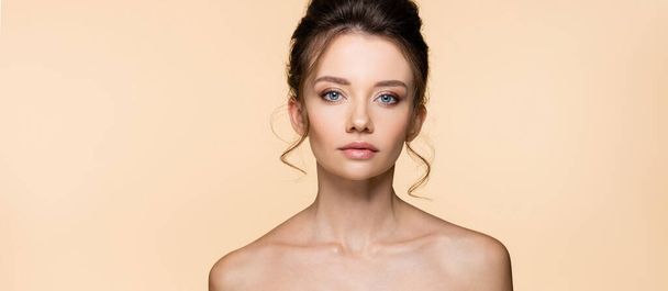 Portrait of brunette model with naked shoulders isolated on beige, banner  - 写真・画像