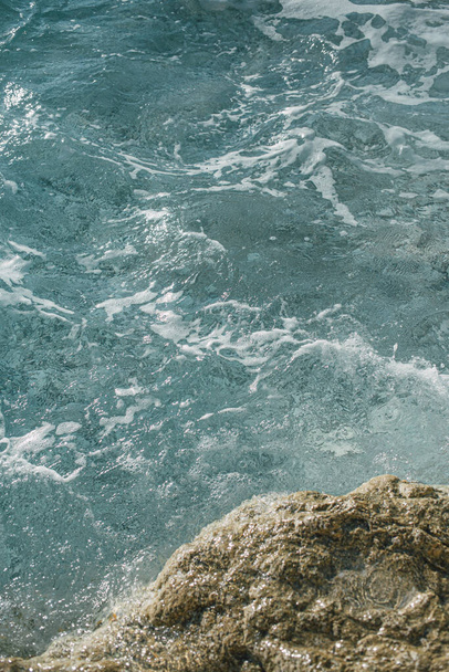 Kustlijn landschap met kristalblauw water en zachte golven met zeeschuim crashen op klif. Mariene texturen en golfpatronen. Oceaanachtergrond. - Foto, afbeelding