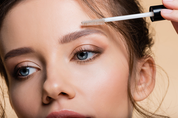 Cropped view of young woman applying eyebrow gel isolated on beige  - Valokuva, kuva