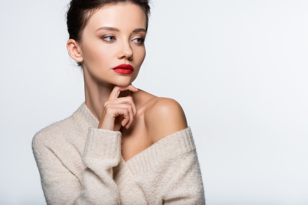 Trendy model in sweater with naked shoulder looking away isolated on white - Φωτογραφία, εικόνα