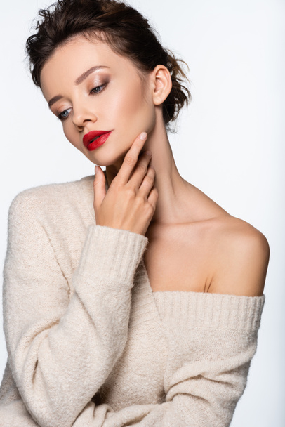 Brunette woman in sweater touching chin isolated on white - Fotó, kép
