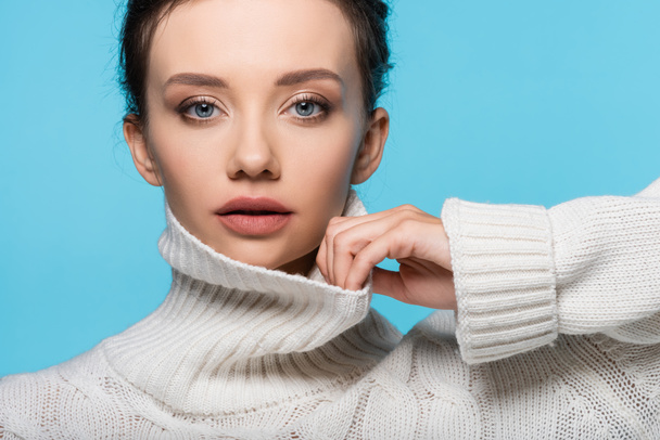 Young model touching collar of knitted sweater isolated on blue - Foto, Bild