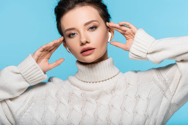 Pretty woman in knitted sweater using earphones isolated on blue - Photo, Image