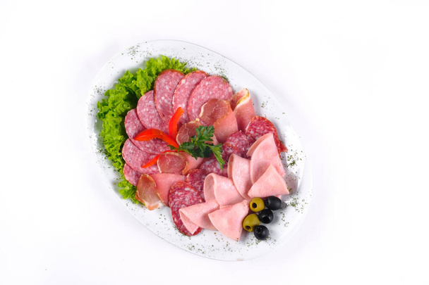 Ham and sausage cut into slices on a plate on a white isolated background. - Photo, Image