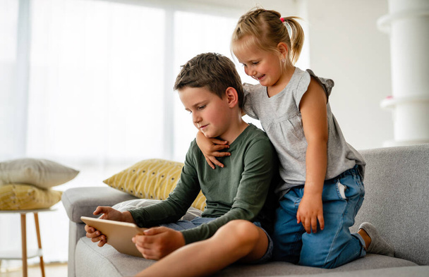 Little girl and boy watching video or playing games on their digital device tablet, smartphone. Children digital addiction concept. - Foto, immagini