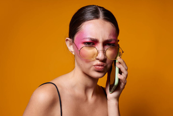 Portrait of beautiful young woman with glasses bright makeup posing black jersey talking on the phone close-up unaltered - Foto, afbeelding