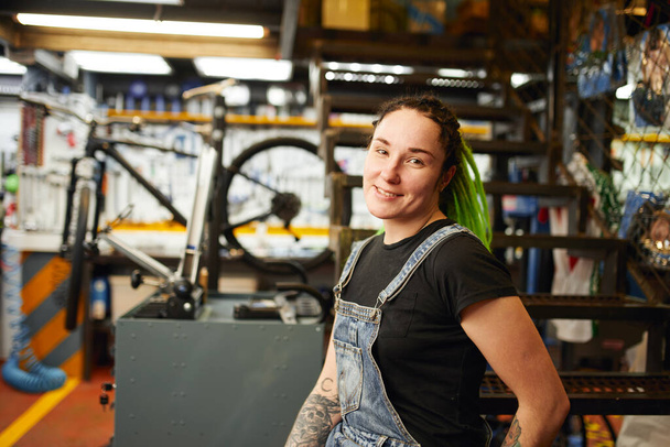 Cheerful mechanic in bike repair shop - Foto, afbeelding
