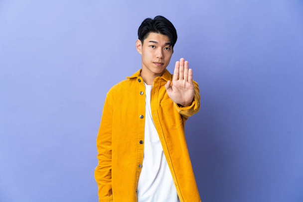 Young Chinese man isolated on purple background making stop gesture - Photo, Image