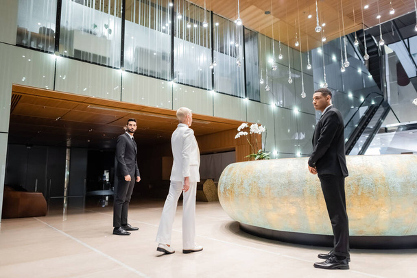 full length view of multicultural security men near stylish businesswoman walking in hotel lobby - Fotoğraf, Görsel
