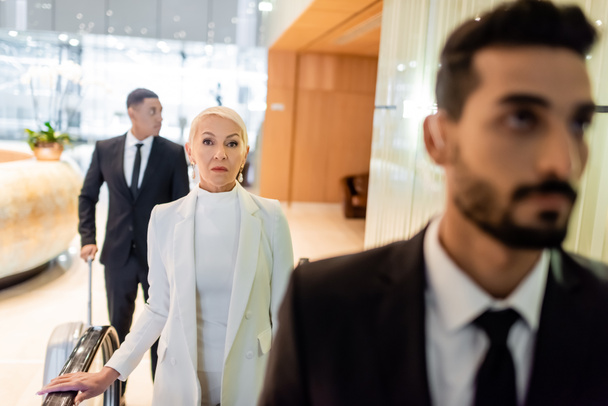 interracial bodyguards protecting senior businesswoman in hotel foyer during business trip - Photo, Image