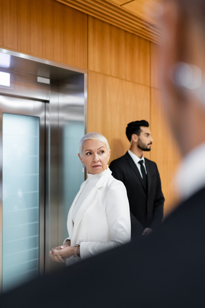 старший охоронець чекає на ліфт біля дворасового охоронця і афроамериканця безпеки на розмитому передньому плані
 - Фото, зображення