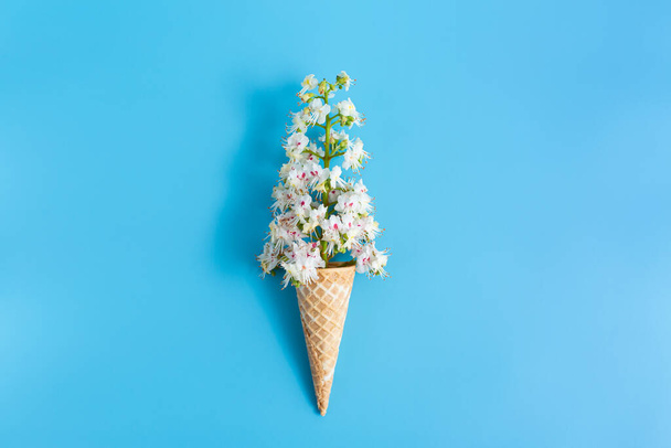Copa de gofres crujiente dulce con flor de castaño sobre un fondo azul - Foto, imagen