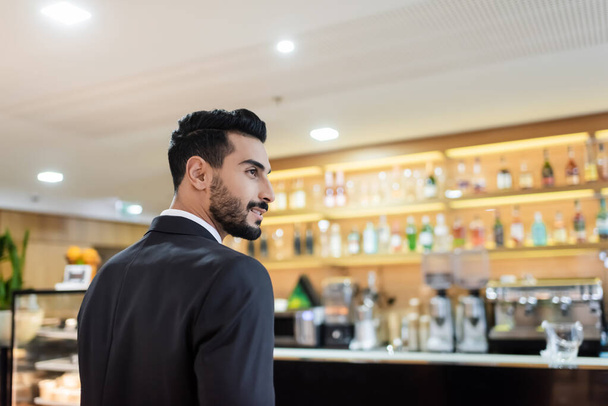 young mixed race guard smiling near blurred lobby bar in hotel - Photo, Image