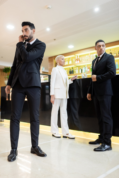 full length view of multicultural bodyguards and trendy business lady at lobby bar in hotel - Photo, Image