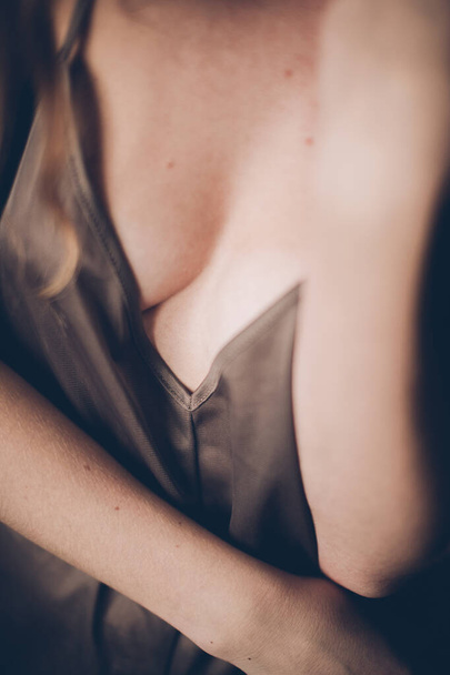 Details of the female body, the girl moves in a brown dress with a combination of straps, light exposure  - Foto, imagen