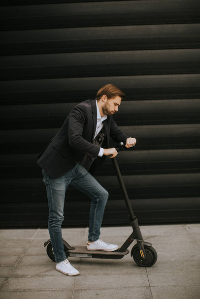 Beau jeune homme d'affaires utilisant le téléphone mobile sur scooter électrique - Photo, image