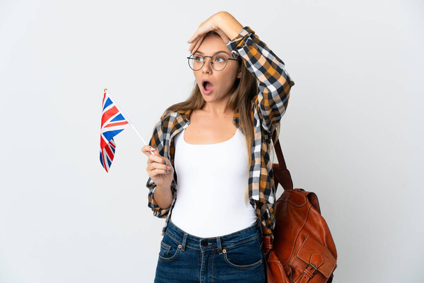 Junge Litauerin mit einer britischen Flagge auf weißem Hintergrund macht überraschende Geste, während sie zur Seite schaut - Foto, Bild
