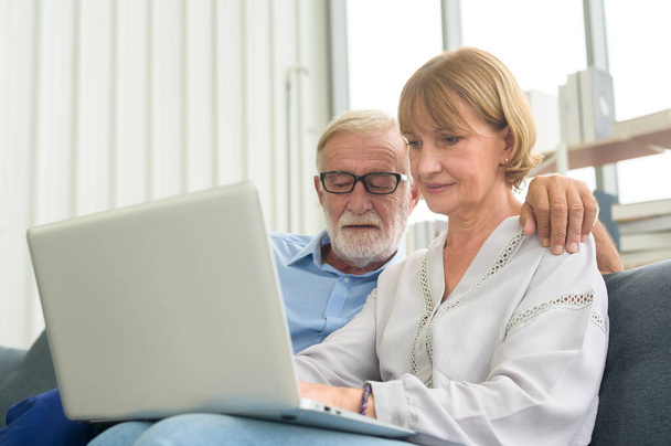 Feliz Caucásico pareja de ancianos utilizando el ordenador portátil en casa - Foto, imagen