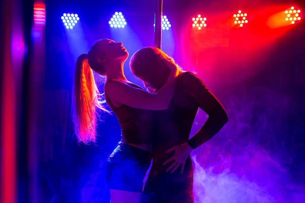 Two young sexy women dancing a striptease near the pylon - Фото, изображение