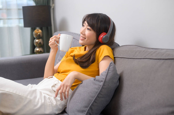 A young happy woman listening to music and relaxing at home - Foto, Imagem