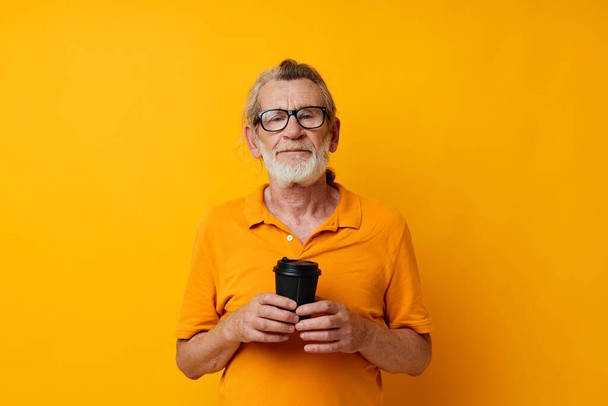 Portrait elderly man with black disposable cup yellow background - Foto, immagini